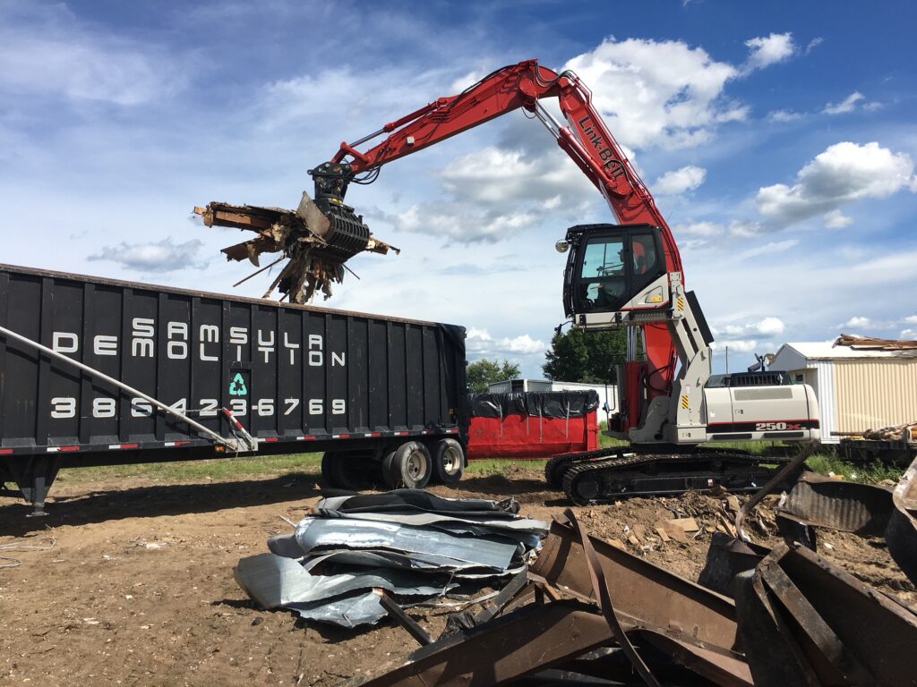 Excavator loading metal onto a truck on a demolition job.
