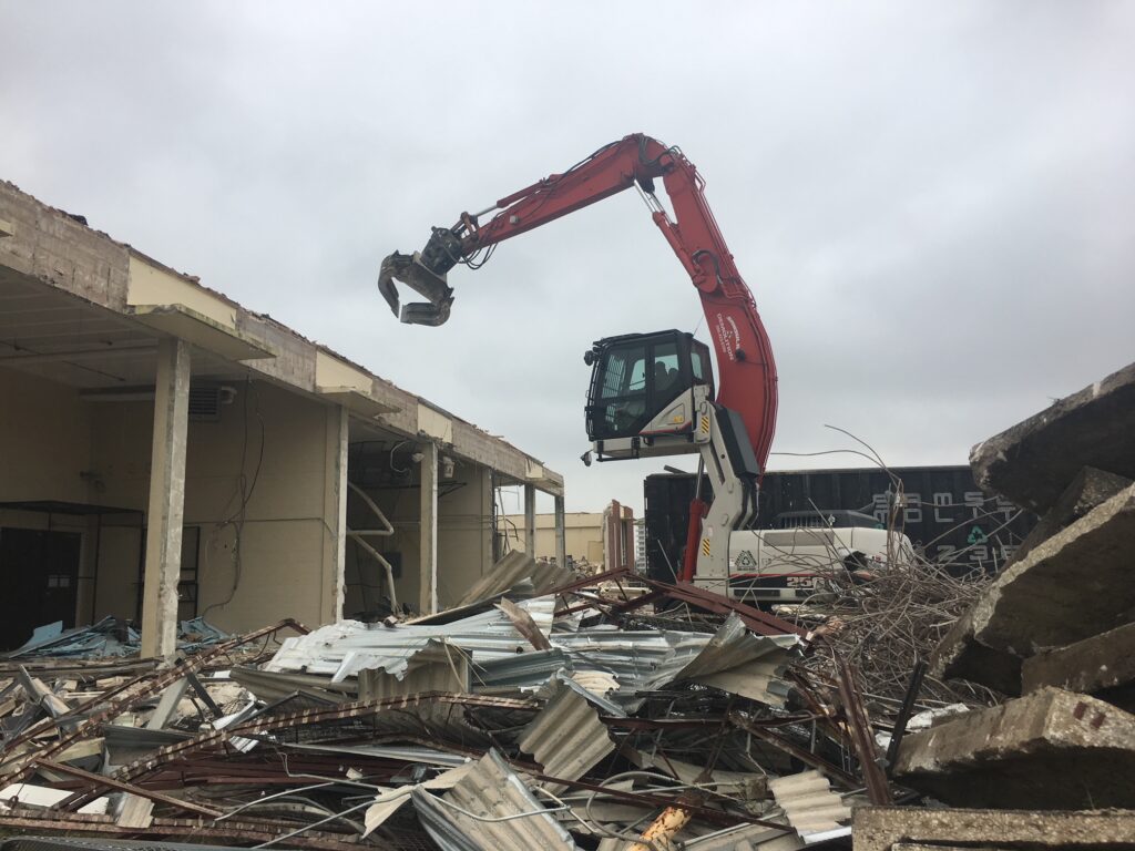 Excavator conduction a demolition of a concrete building to recycle it.